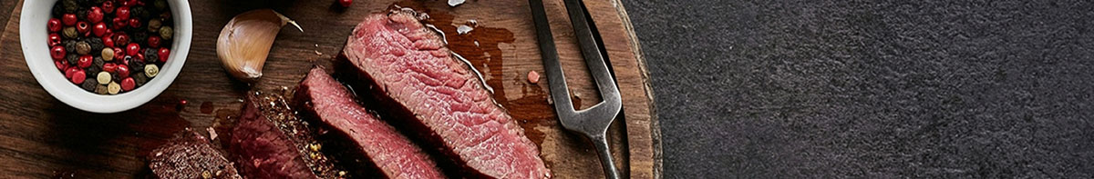 Medium rare steak hot off the grill with meat fork and spices.